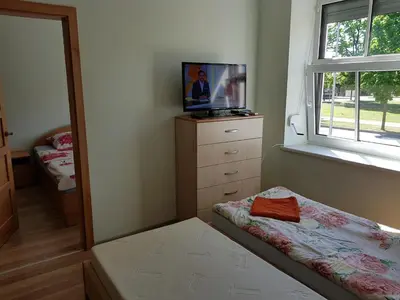 a bedroom with a bed and a dresser and a window at Rodante Apartments in Druskininkai
