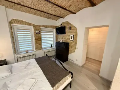 a bedroom with a bed and a tv and windows at Šopeno Old Town Apartments in Vilnius