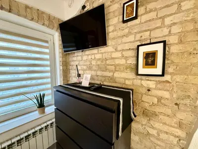 a tv on a stone wall with a dresser at Šopeno Old Town Apartments in Vilnius