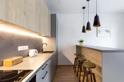 a kitchen with white cabinets and bar stools at Cosy Central Apartments by Reside Baltic in Vilnius