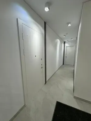 a hallway with white walls and white doors and a rug at Rambynas R36 in Panevėžys