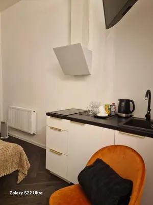 a kitchen with a black counter and a orange chair at Kaunas Studios - RentA Studio 16 in Kaunas
