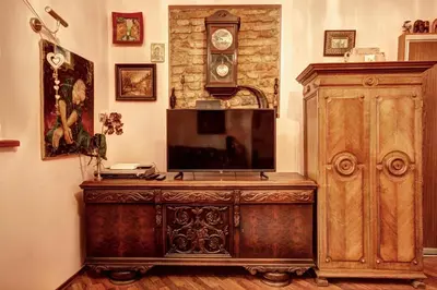 a large wooden dresser with a clock on a wall at Sofijos apartamentai Old Town in Vilnius