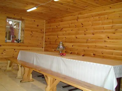 a wooden room with a table with a white table cloth at Leon's farmstead in the countryside, Sauna and Jacuzzi for 16-23 people in Užuperkasis