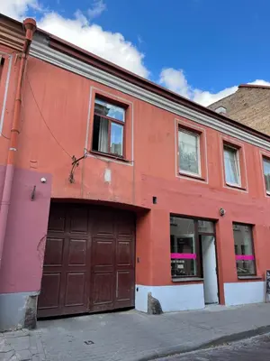 an orange building with two garage doors on a street at Old Town Loft in Vilnius