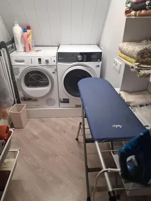 a laundry room with a washing machine and a blue chair at Šermukšniai in Rokiškis