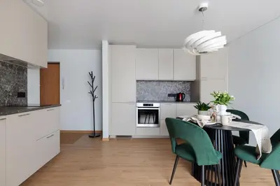 a kitchen with a dining table and green chairs at Cozy 1BD with Bathtub Close to Old Town in Vilnius