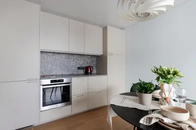 a kitchen with white cabinets and a dining table at Cozy 1BD with Bathtub Close to Old Town in Vilnius