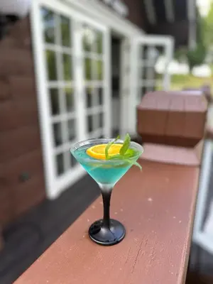a blue drink in a martini glass on a table at Sodyba Barracuda in Kupščiai