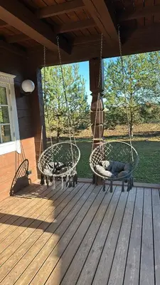 a porch with two swing chairs on a deck at Sodyba Barracuda in Kupščiai