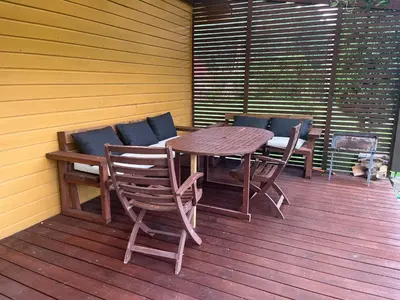 a wooden table and chairs on a wooden deck at Namelis Saulės gatvėje prie Siesarties ežero in Molėtai