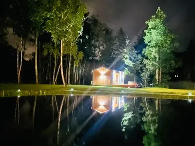 a house is reflected in a pond at night at Dubinga River Valley House & SPA - FREE sauna in Kabakelis