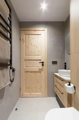 a bathroom with a wooden door and a sink at Dubinga River Valley House & SPA - FREE sauna in Kabakelis