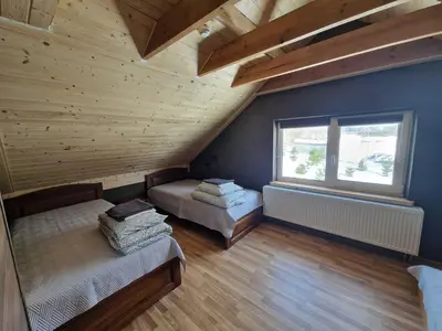 a attic room with two beds and a window at Gardenvillage house in Daržininkai