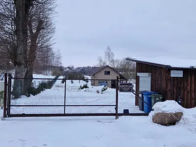 a gate in a snowy yard with a building at Gardenvillage house in Daržininkai