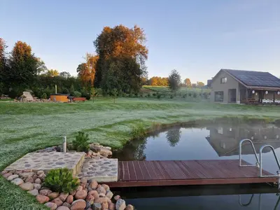 a wooden bridge over a pond next to a house at Gardenvillage house in Daržininkai