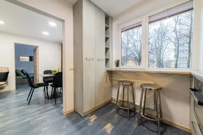 a kitchen with stools and a bar with a window at Greimo Apartments in Šiauliai
