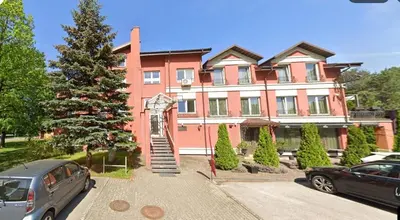 a large pink house with a staircase in front of it at PERLOS apartamentai 2a in Birštonas