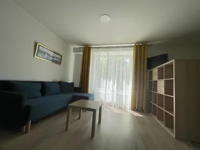 a living room with a blue couch and a table at PERLOS apartamentai 2a in Birštonas
