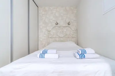 a white bed with blue and white towels on it at Skroblu 39, cozy apartment in Vilnius