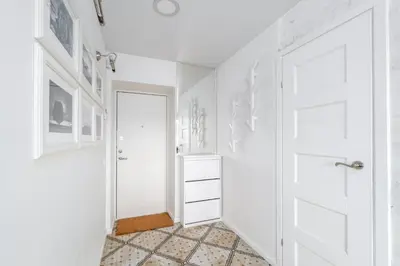 a hallway with a white door and a tiled floor at Skroblu 39, cozy apartment in Vilnius