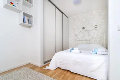 a white bedroom with a white bed with blue accents at Skroblu 39, cozy apartment in Vilnius