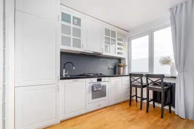 a kitchen with white cabinets and a table and chairs at Skroblu 39, cozy apartment in Vilnius