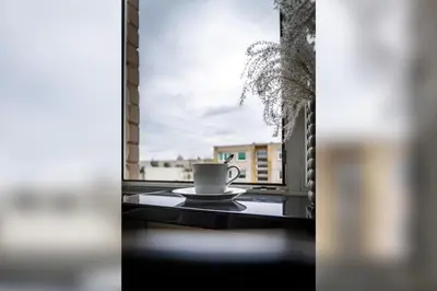 a cup of coffee sitting on a table in front of a window at Skroblu 39, cozy apartment in Vilnius
