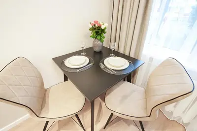 a black table with two chairs and a vase of flowers at Stylish studios near the city center in Vilnius