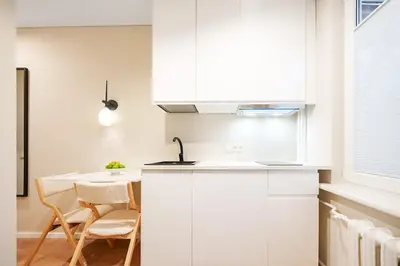 a kitchen with white cabinets and a table and chairs at Stylish studios near the city center in Vilnius