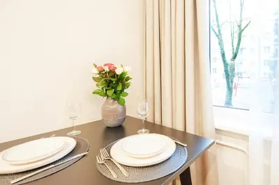 a table with plates and glasses and a vase with flowers at Stylish studios near the city center in Vilnius