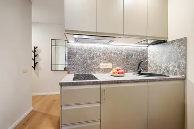 a kitchen with white cabinets and a bowl of fruit on the counter at Stylish studios near the city center in Vilnius