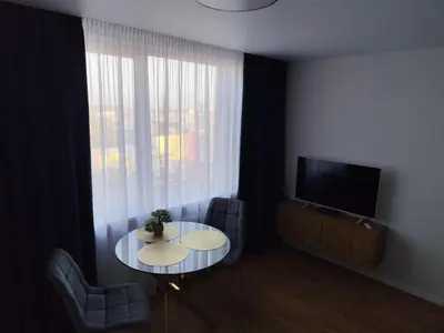 a living room with a table and a television at Itaja apartment 73 in Šiauliai