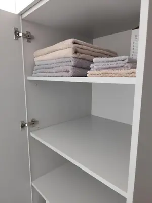 a white closet with white towels on shelves at Itaja apartment 73 in Šiauliai