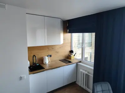 a kitchen with white cabinets and a window at Itaja apartment 73 in Šiauliai