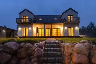 a house with a stone wall in front of it at Picturesque Villa RestArt by Reside Baltic in Nemenčinė