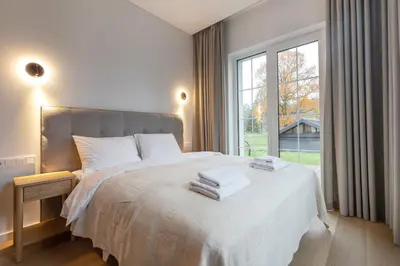a bedroom with a white bed with a large window at Picturesque Villa RestArt by Reside Baltic in Nemenčinė