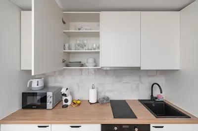 a kitchen with white cabinets and a sink and a microwave at Apartment Dandelion by Polo Apartments in Kaunas
