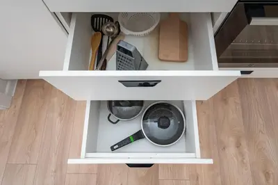 a white cabinet with utensils in it at Apartment Dandelion by Polo Apartments in Kaunas