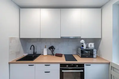 a kitchen with white cabinets and a sink at Studio apartment Sea by PoloApartments in Kaunas