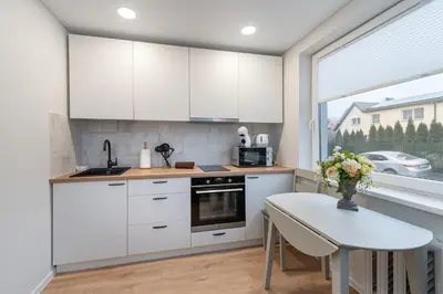 a kitchen with white cabinets and a table and a window at Studio apartment Sea by PoloApartments in Kaunas