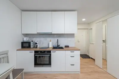 a white kitchen with white cabinets and appliances at Studio Apartment Flora by PoloApartments in Kaunas