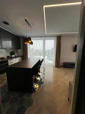 a living room with a table and a kitchen at WAVE Apartaments Vilnius in Vilnius