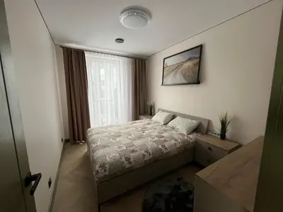 a small bedroom with a bed and a window at WAVE Apartaments Vilnius in Vilnius