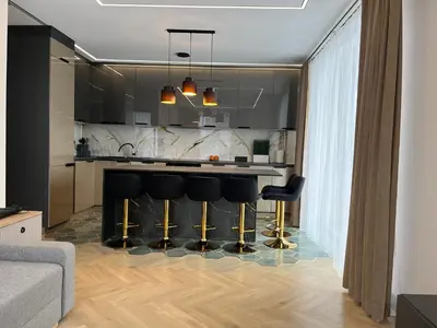 a kitchen with a bar with black bar stools at WAVE Apartaments Vilnius in Vilnius