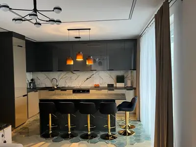 a kitchen with black cabinets and black bar stools at WAVE Apartaments Vilnius in Vilnius