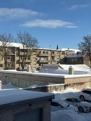 a snow covered parking lot in front of a building at Cosy little studio in Šiauliai