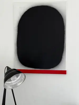 a black and red picture and a lamp on a wall at Cosy little studio in Šiauliai