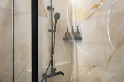 a shower with a shower head in a bathroom at Vilniaus 99 Apartamentai in Šiauliai