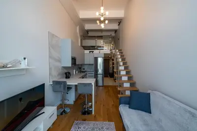 a living room with a staircase leading up to a loft at Charlotte loft in Vilnius
